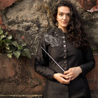 Portrait photo of a woman with long dark curly hair standing against a brick wall